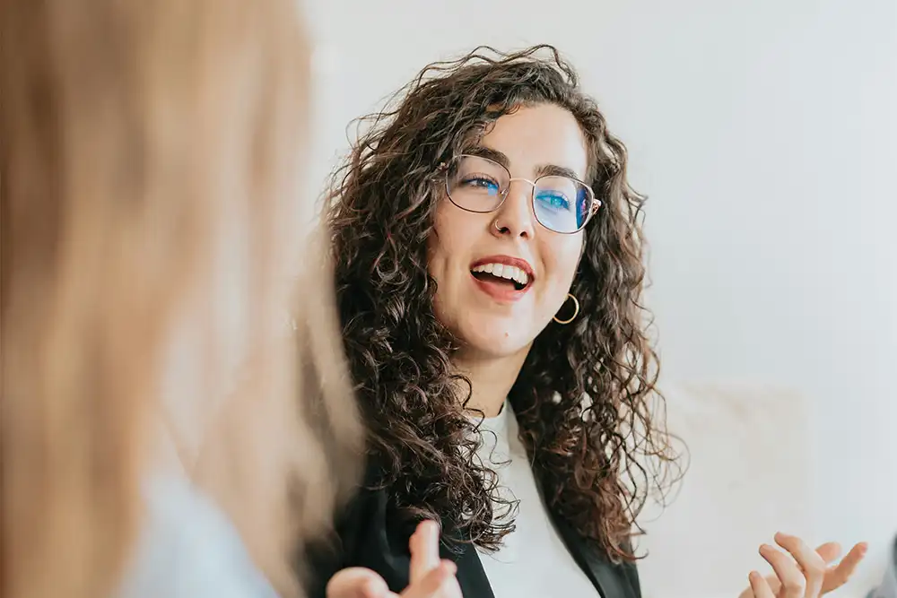 Two women engaged in a discussion in a meeting room, focusing on education and mental illness awareness