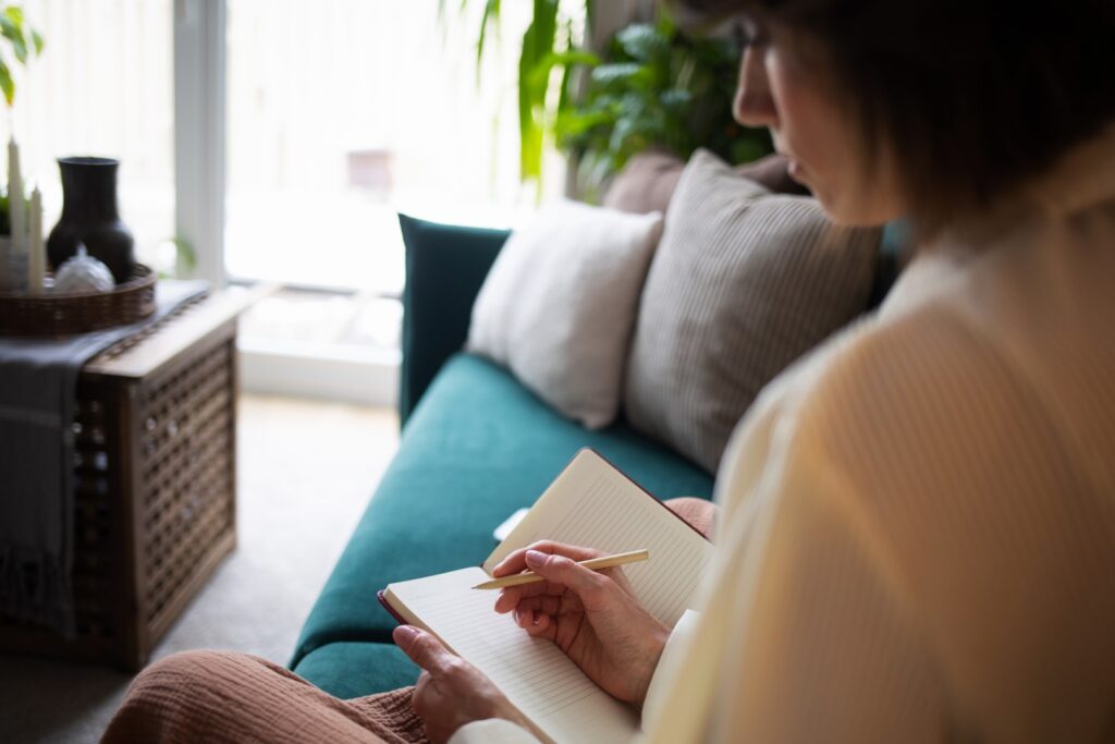 Adult woman journaling on sofa indoors at home