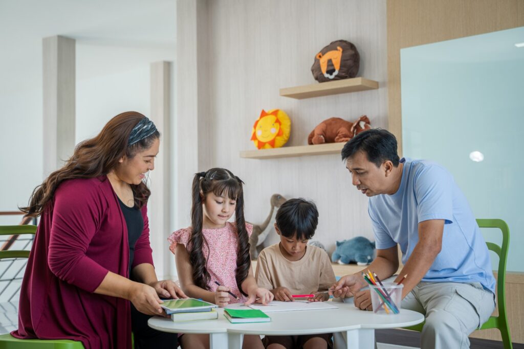 Adults and children drawing together at white tabl