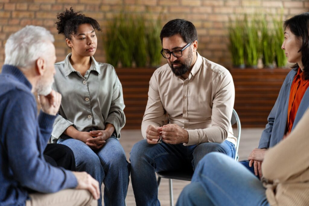 Diverse people sitting in circle supporting each o