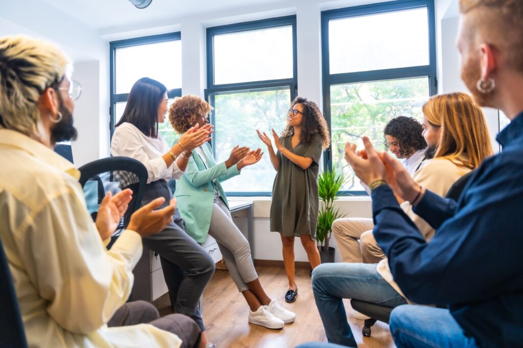 Group applauding colleague s speech in bright offi