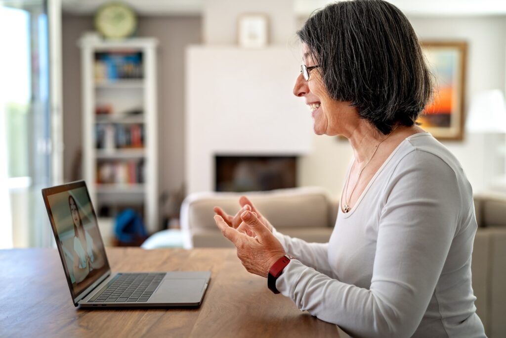 Senior woman video calling on laptop at home