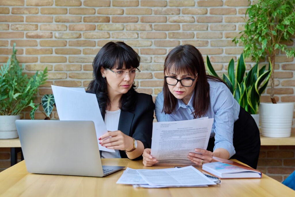 Two mature serious confident business women workin