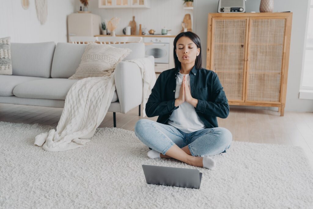 Woman meditating cross legged on rug at home