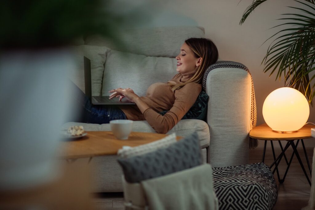 Woman relaxing on sofa with laptop at home