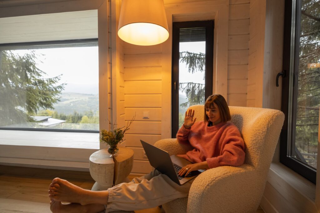 Woman works on laptop at house in mountains